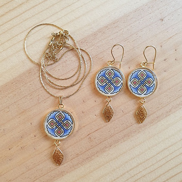 Halskjede anheng belyst med bl&aring; palmetter, gull og r&oslash;d sammenfletting p&aring; gullkjede