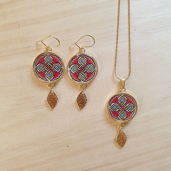 Halskjede anheng belyst med bl&aring; palmetter, gull og r&oslash;d sammenfletting p&aring; gullkjede