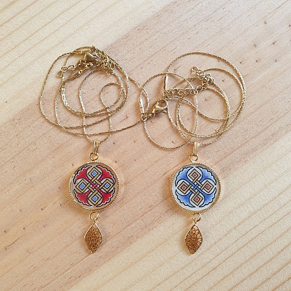 Halskjede anheng belyst med bl&aring; palmetter, gull og r&oslash;d sammenfletting p&aring; gullkjede