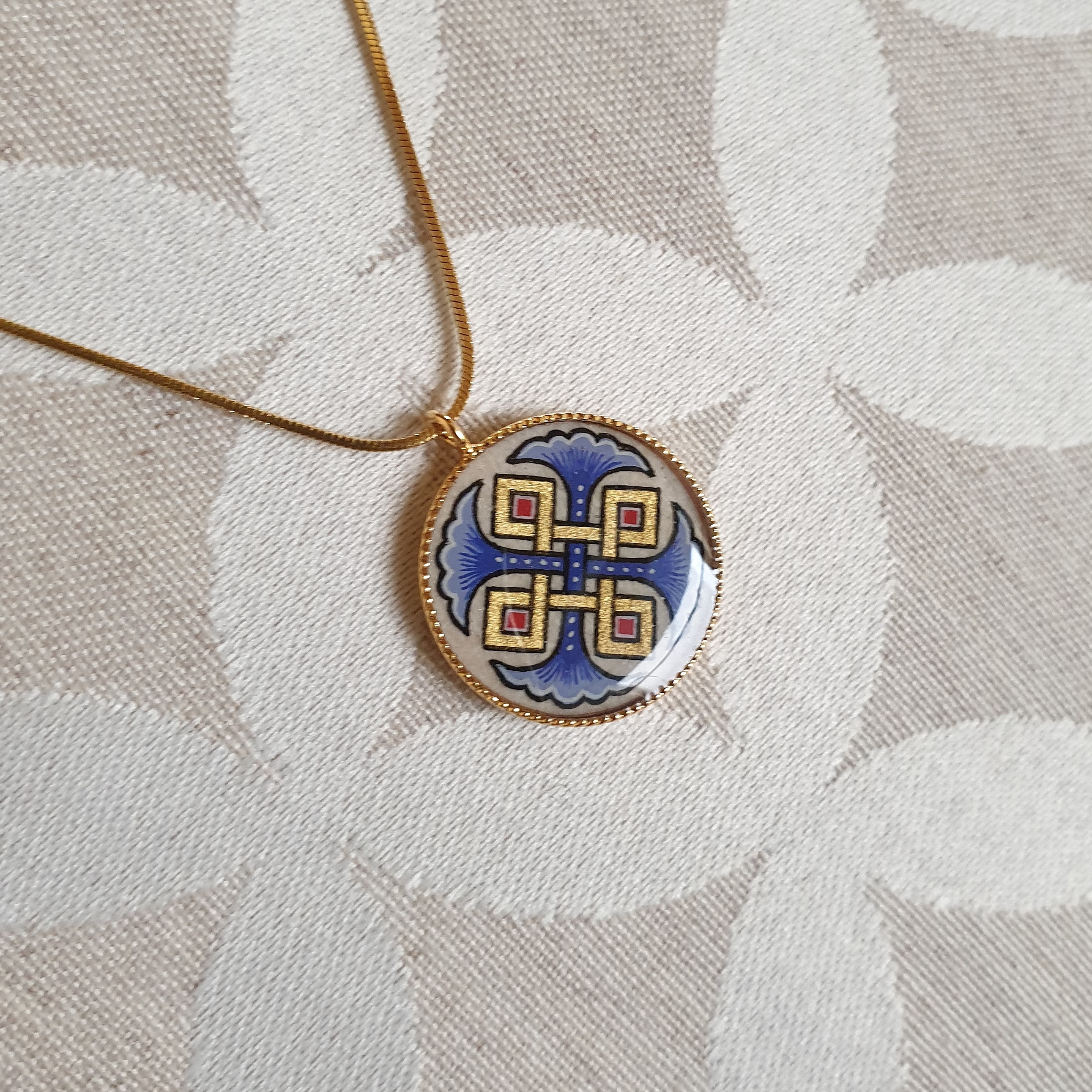 Halskjede med anheng med bl&aring; palmetter, gull og r&oslash;dt flettverk p&aring; gullkjede