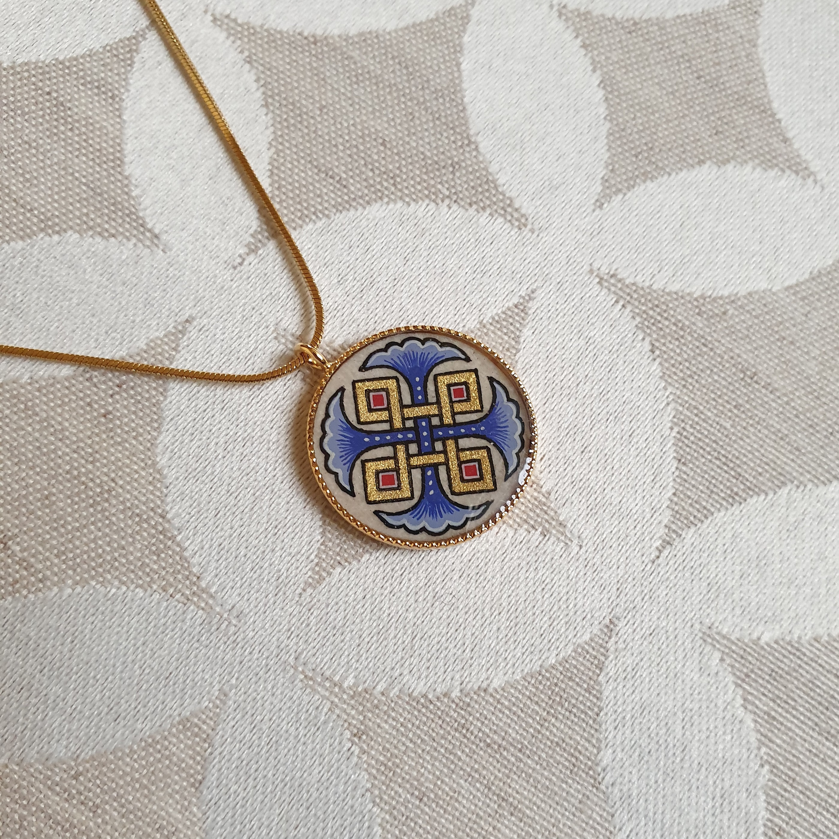 Halskjede med anheng med bl&aring; palmetter, gull og r&oslash;dt flettverk p&aring; gullkjede